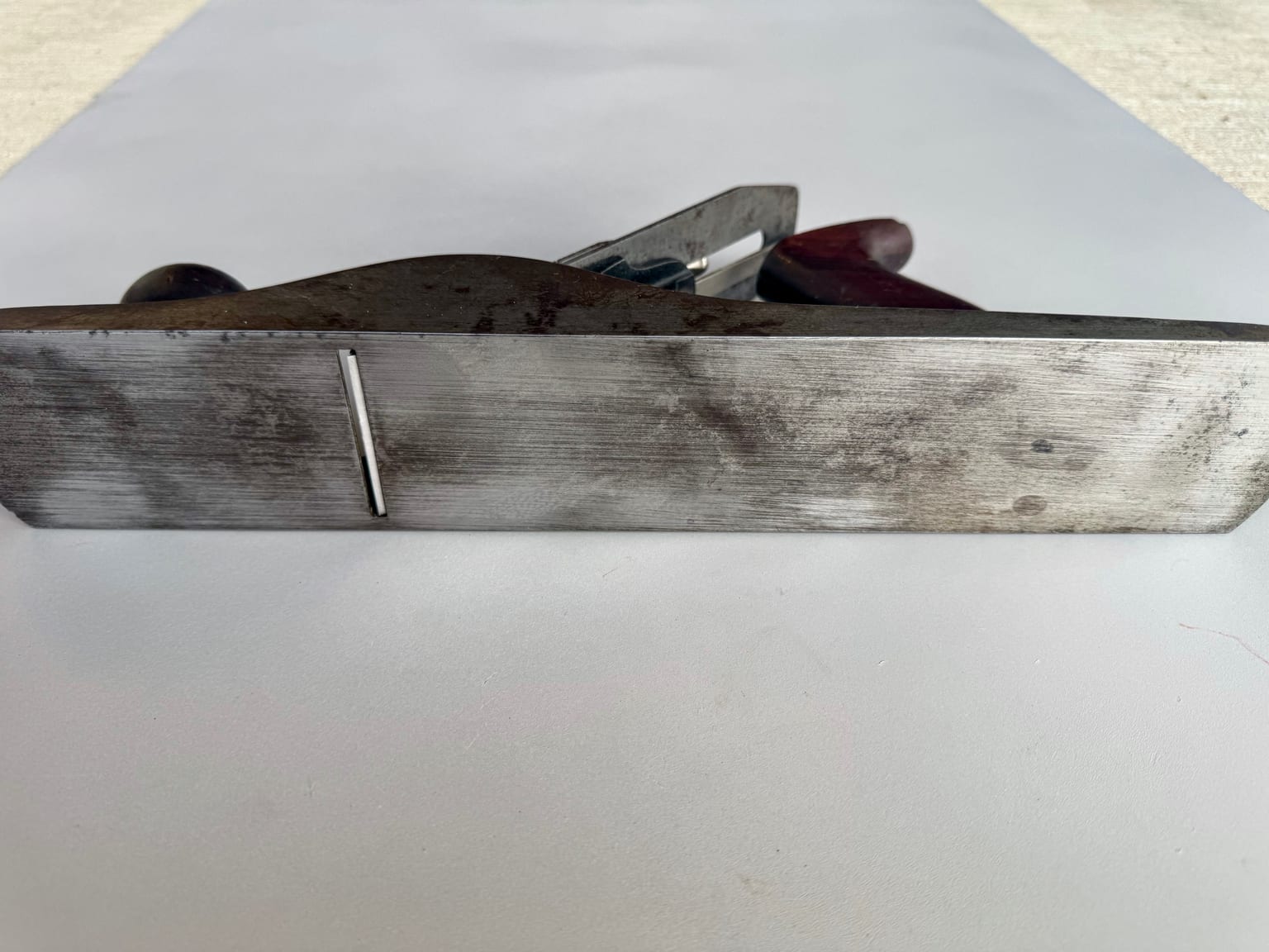 Close side view of a restored Stanley Bailey No. 5 showing a lapped sole edge alongside retained staining and pitting on the cheek